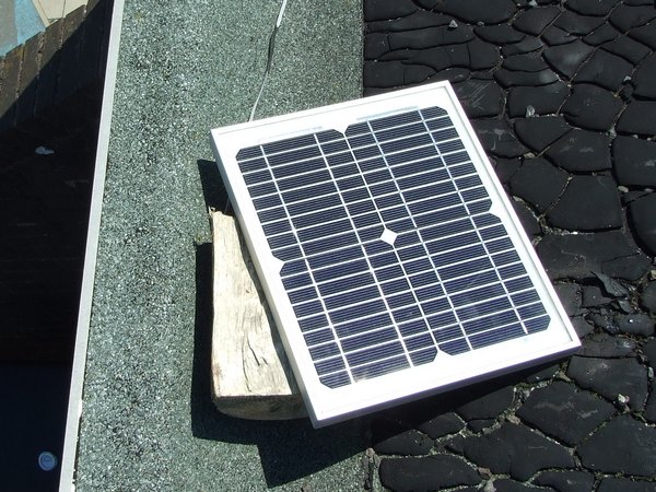 A simple small 10W solar panel, resting on a flat roof